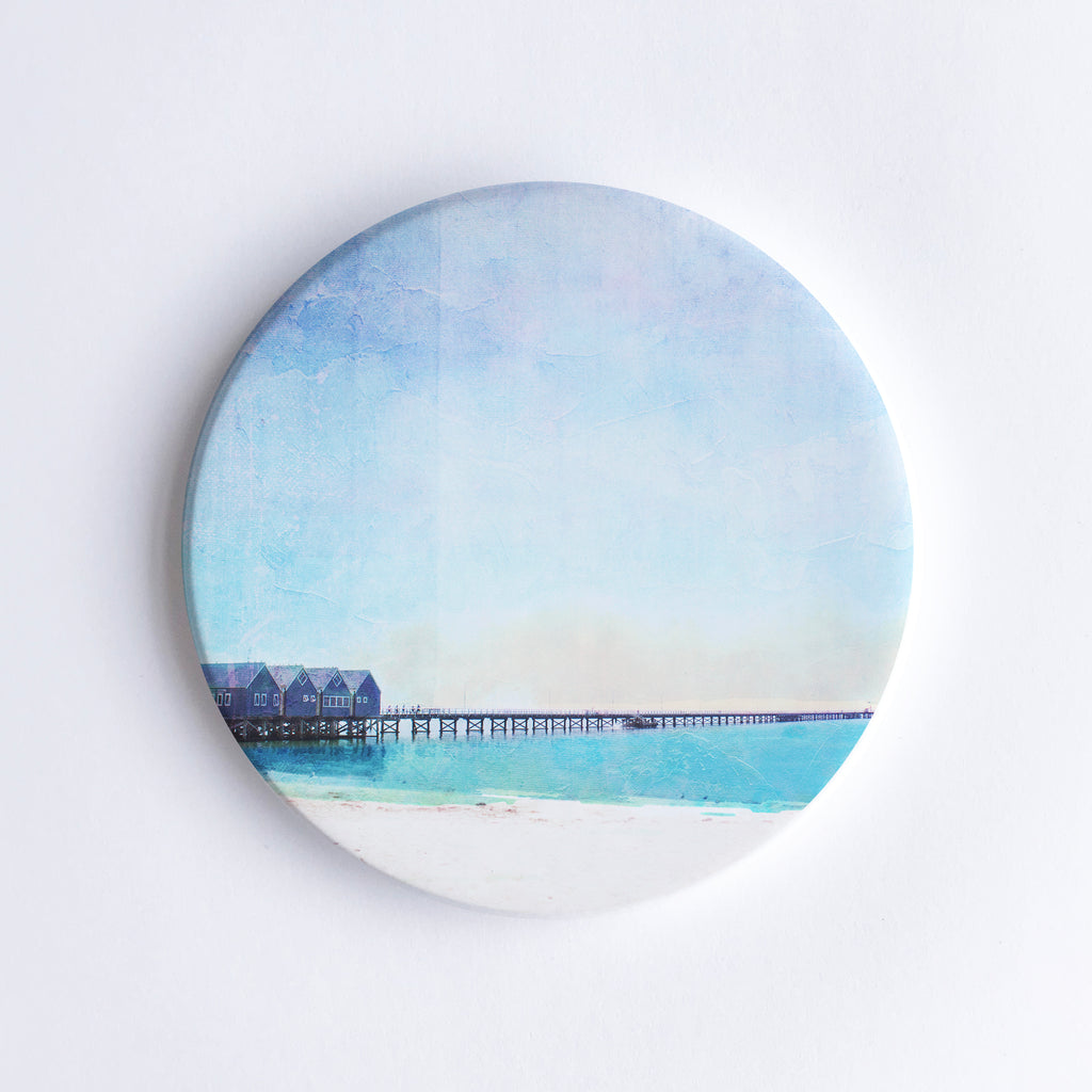 Round, hand printed ceramic coaster with illustration of Busselton Jetty which consists of 4 boathouses on a 1.8km timber jetty over the ocean.