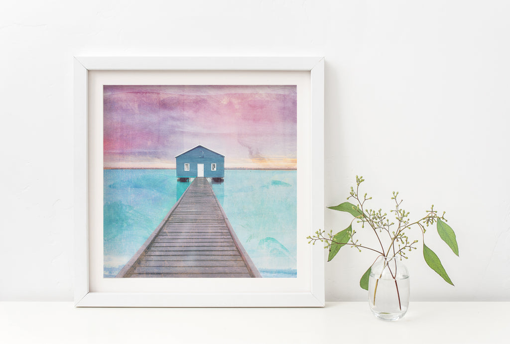 Illustration art print of the blue Crawley Boathouse at the end of the pier with turquoise water and pink sky. 