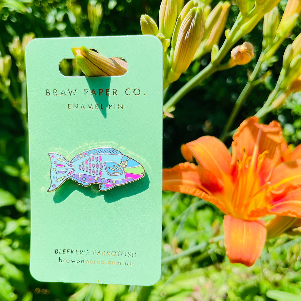 Parrotfish enamel pin on a green card with a floral background