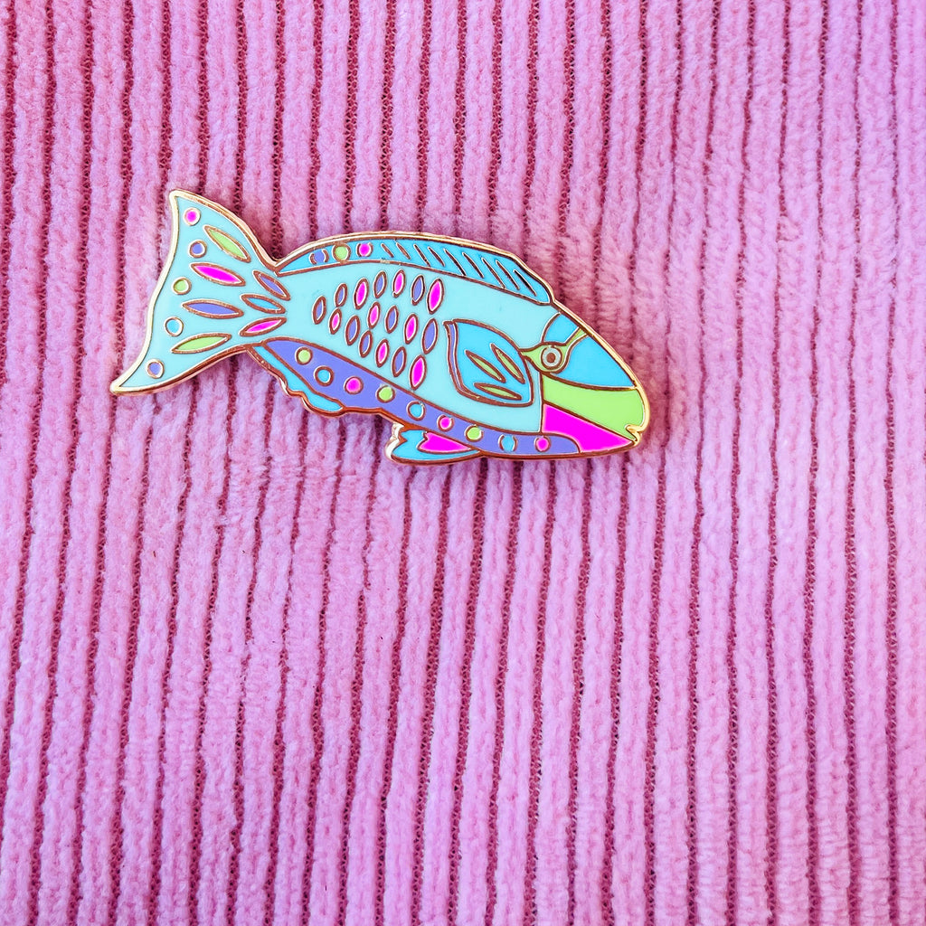 Colourful Parrotfish shaped pin on a pink textured background