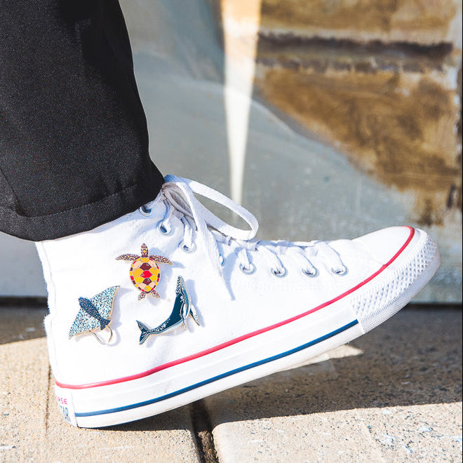 Humpback Whale Enamel Pin, Sea Turtle Enamel Pi, Eagle Ray Enamel Pin on a white converse high-top trainer. Braw Paper Co