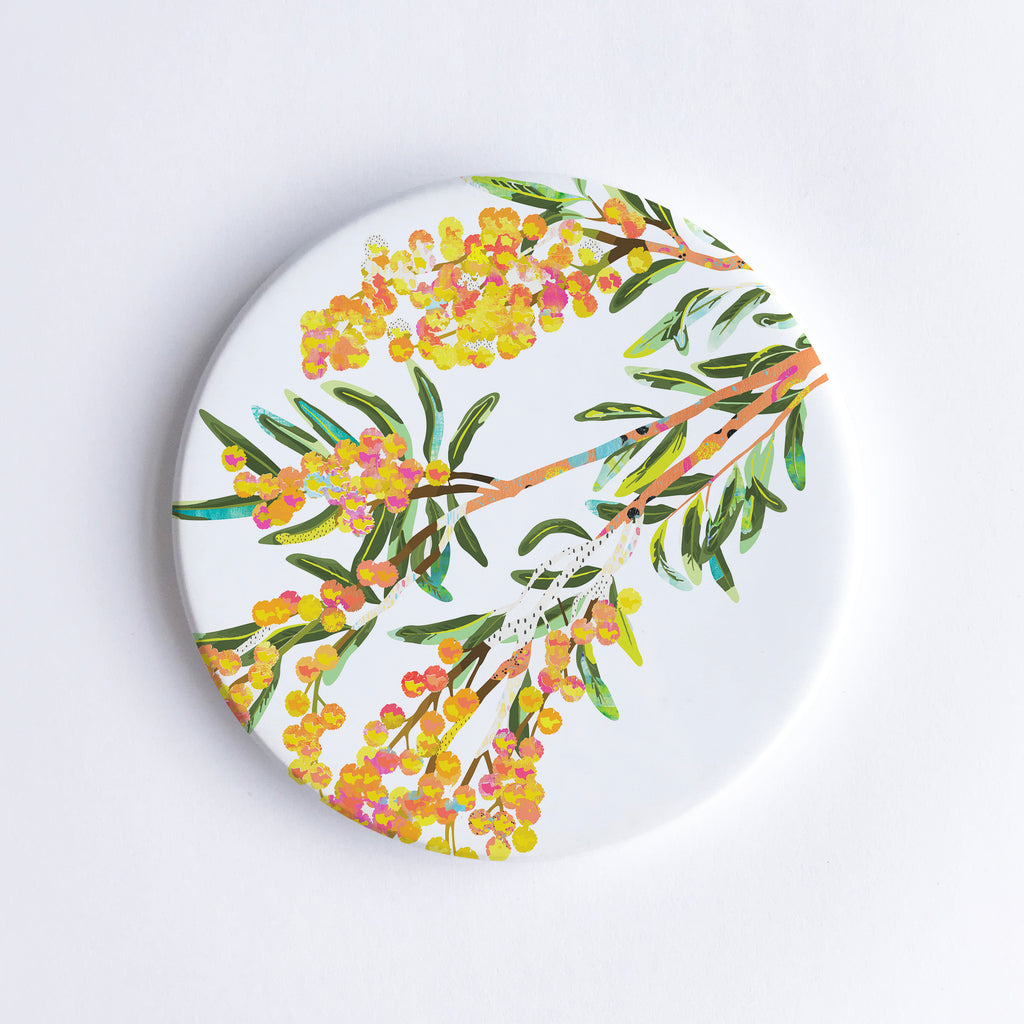 Round white ceramic coaster with a yellow, orange, green Acacia flower illustration.