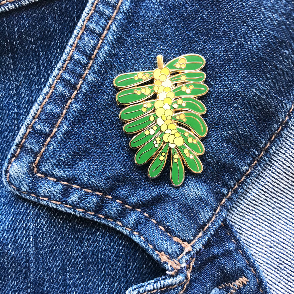Enamel pin with yellow and green Acacia or wattle flower illustration. 