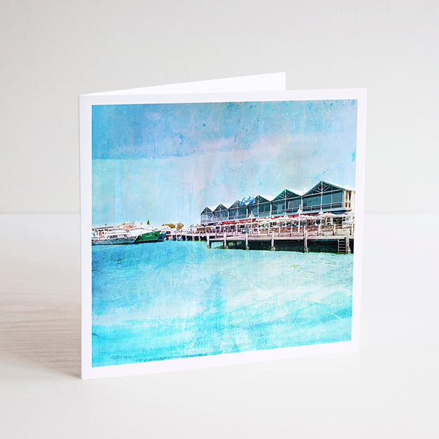 Square notecard with illustration of Fremantle Fishing Boat Harbour and Kaili’s fish restaurant on stilts over the water.