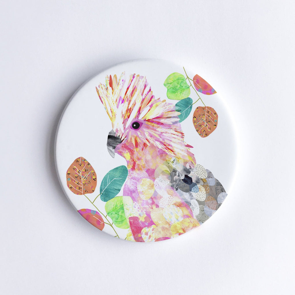 Round, hand printed ceramic coaster with illustration of a pink, white and grey Galah bird on white background.