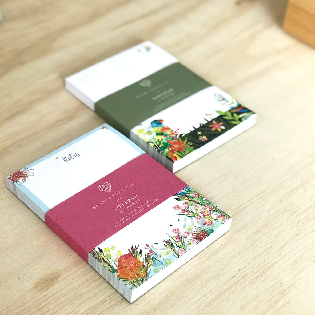 Two blank A6 notepads next to each other with colourful Australian native fauna and flora illustrations.