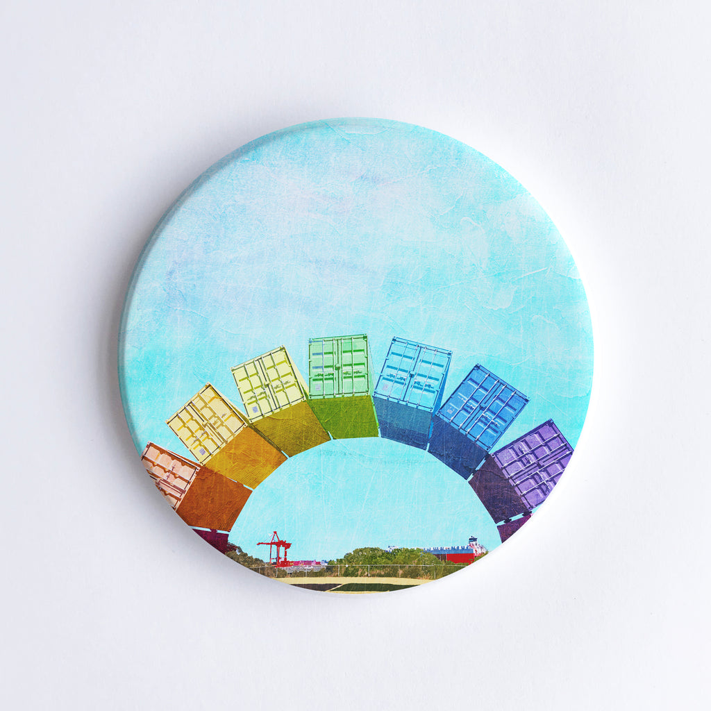 Round, hand printed ceramic coaster with illustration of Fremantle Rainbow Shipping Containers and Fremantle Harbour with cranes and a cargo ship in the background.